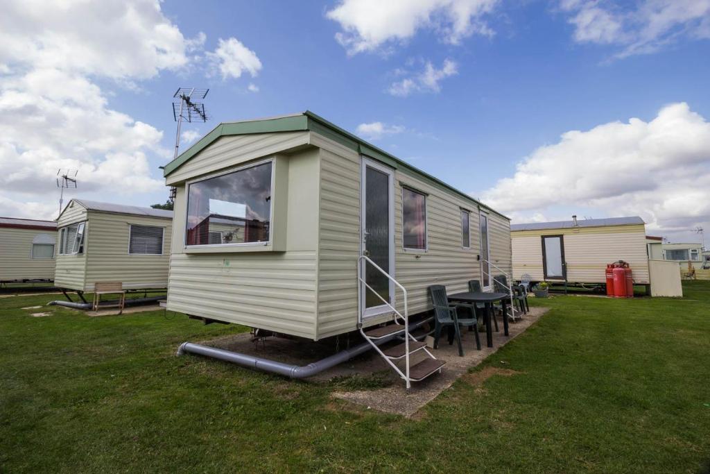 a green and white tiny house with a table and chairs at 6 Berth Caravan For Hire At Martello Beach Holiday Park In Essex Ref 29017y in Clacton-on-Sea
