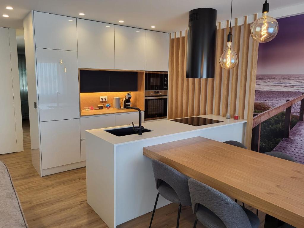 a kitchen with white cabinets and a wooden table at Apartamento Cinema para férias em Esposende in Esposende