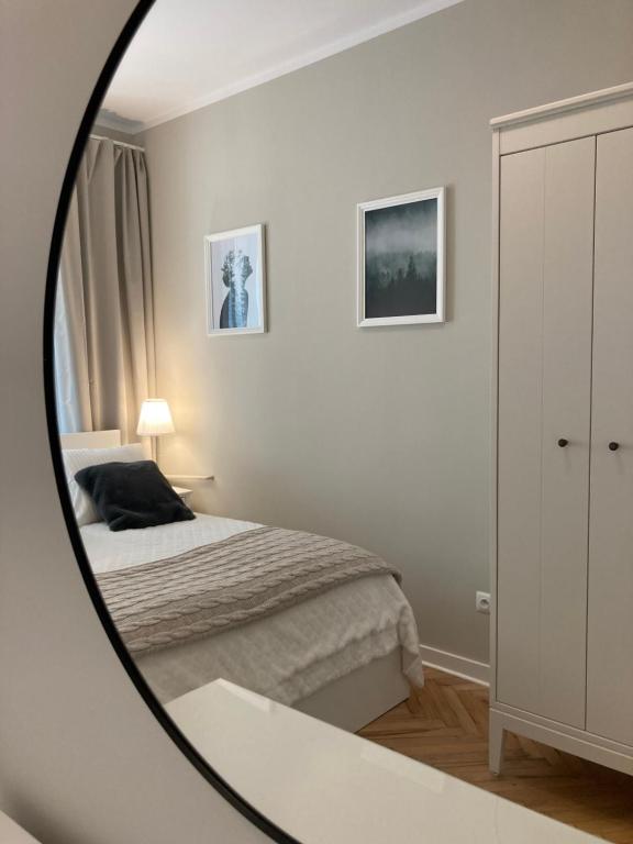 a white bedroom with a bed and a mirror at Apartment BB II nad Deptakiem in Krynica Zdrój