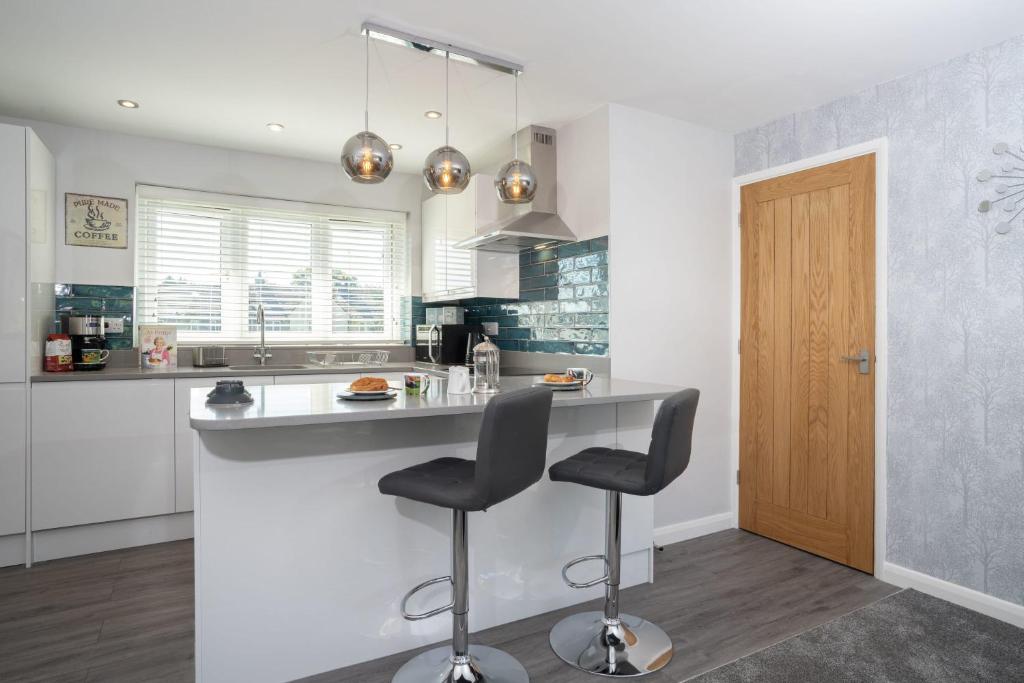 a kitchen with a counter and a bar with two stools at Kentmere Haven - 2 Bedroom - Cycle Storage in Kendal