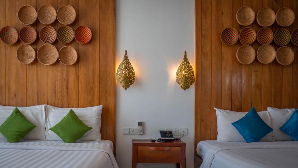 a hotel room with two beds and wooden walls at Vihara The City of Temples in Siem Reap