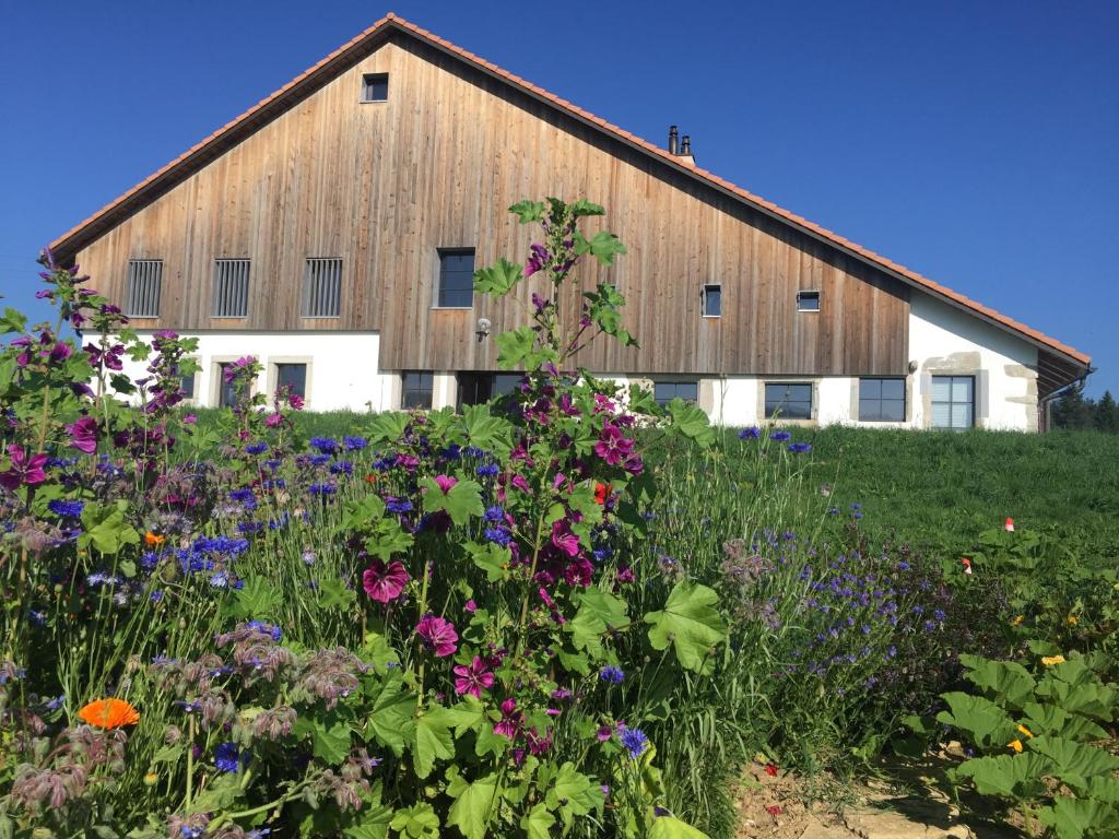 a barn with a field of flowers in front of it at Brasel in La Brévine