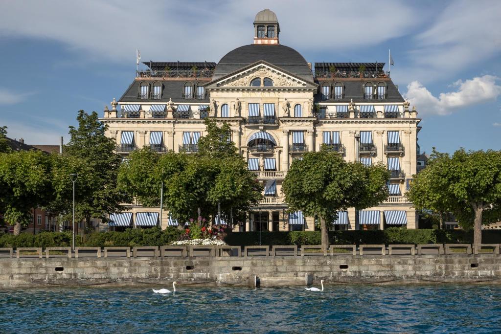 een groot gebouw naast een waterlichaam bij La Réserve Eden au Lac Zurich in Zürich