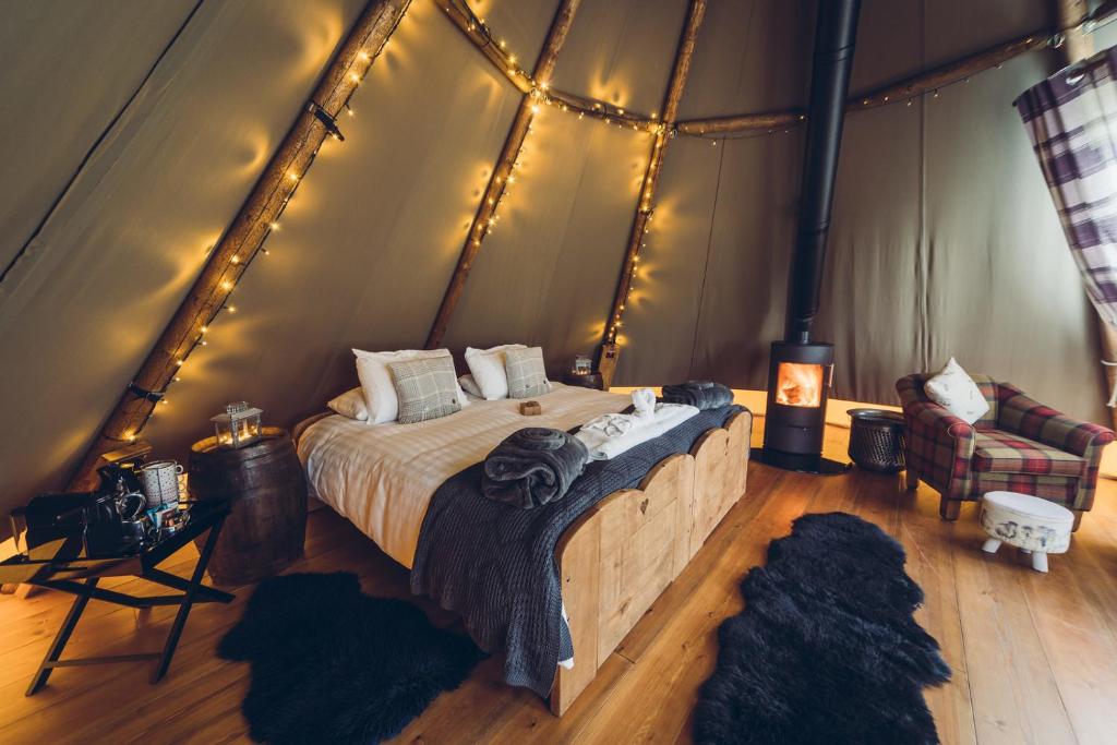 a bedroom with a bed in a tent with lights at Scaldersitch Farm Boutique Camping Tipi with private wood fired hot tub in Sheen