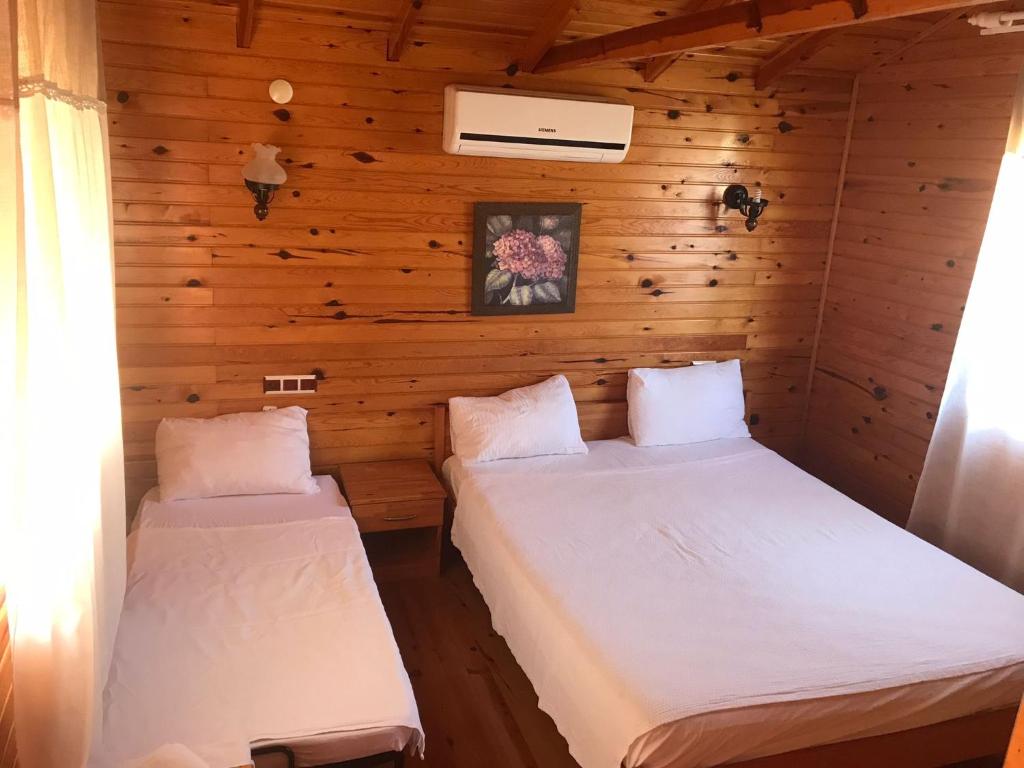 KumlucaAda Adrasan Hotel的一间木墙房间里有两张床