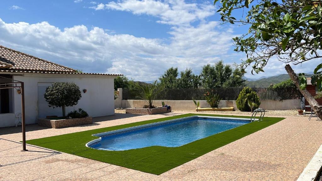 una piscina con césped junto a una casa en La Casa Arboleas, en Arboleas