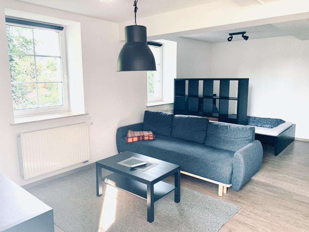 uma sala de estar com um sofá azul e uma mesa em Apartment im Gästehaus Matzmühle Ruhland (6-8 P.) em Ruhland