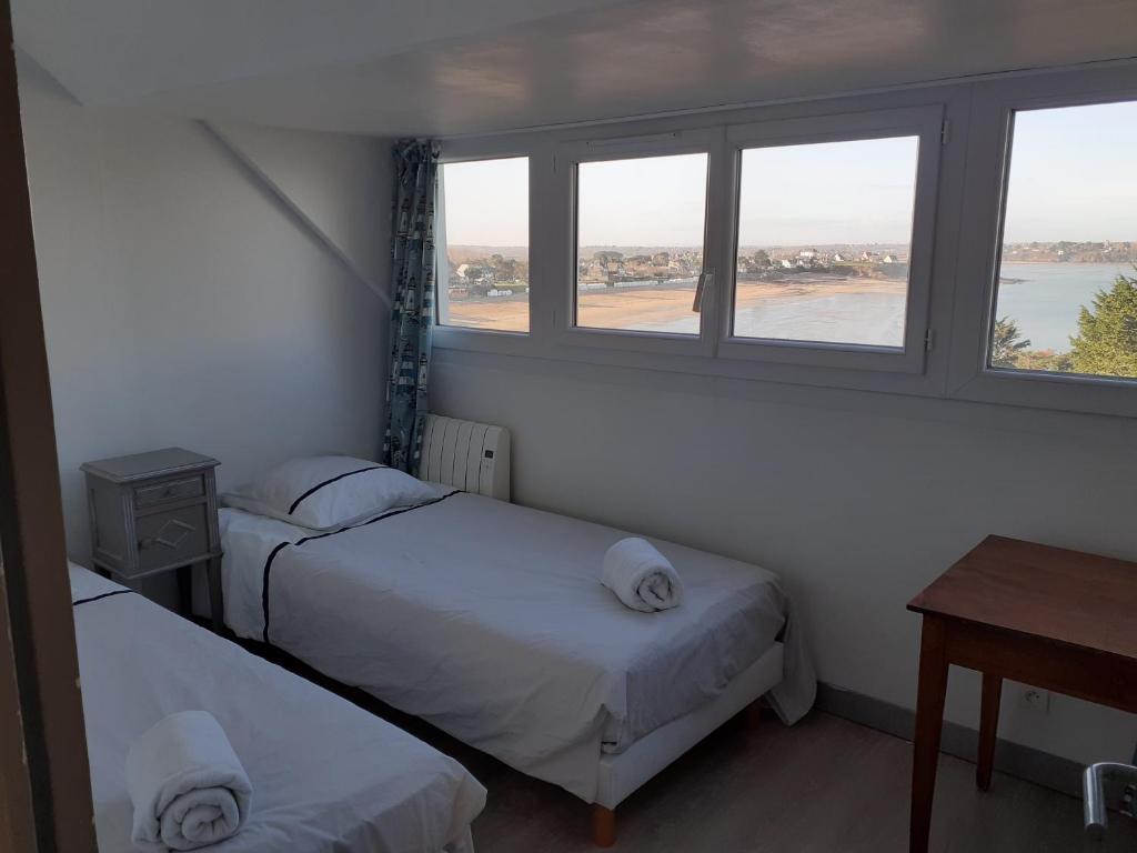 - 2 lits dans une chambre avec 2 fenêtres dans l'établissement Maison vue exeptionnelle sur la mer, à Lancieux