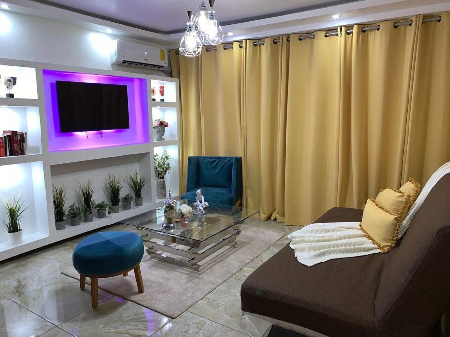 a living room with a couch and a table and a tv at Romantic Studio w/Jacuzzi 15 min Airport in Ensanche Los Minas
