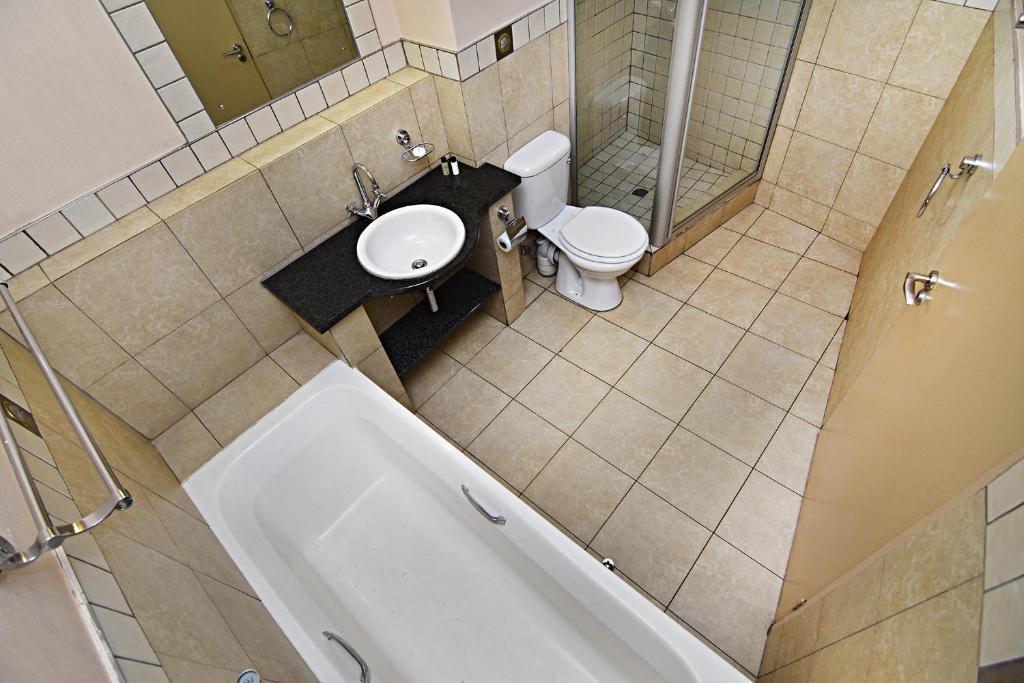 uma casa de banho com um WC, um lavatório e uma banheira em The Gold Hut em Joanesburgo
