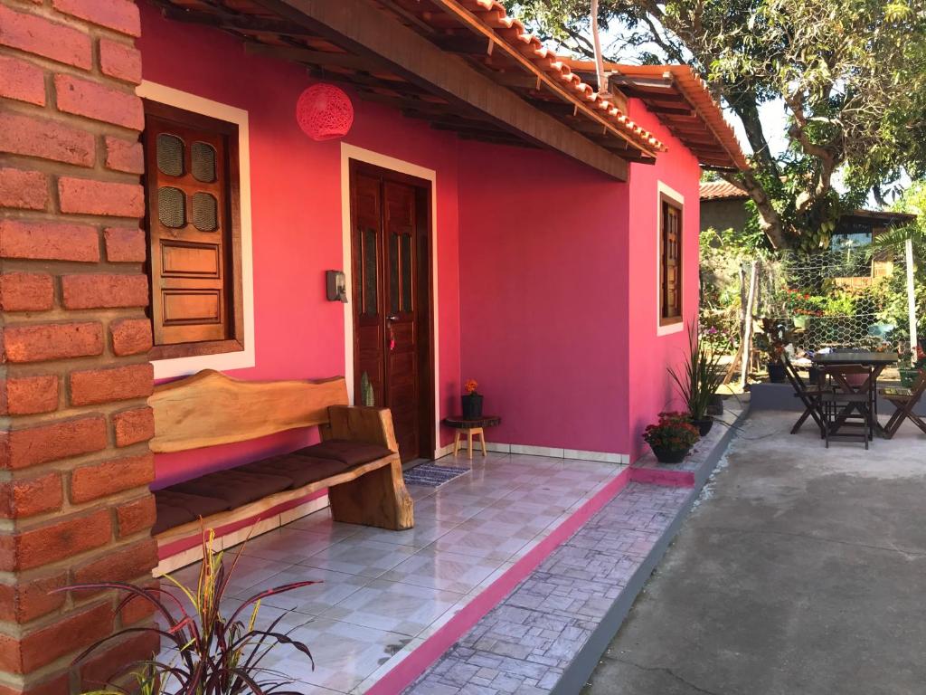 a red house with a bench on a patio at Casa Rosa in Vale do Capao