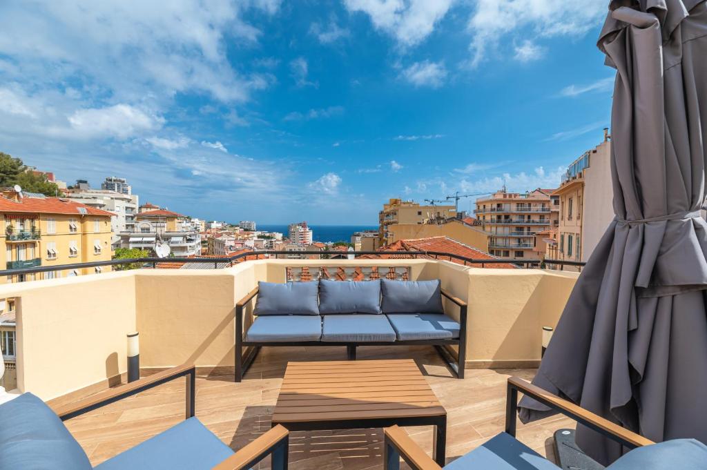 a balcony with a couch and a view of the city at SUPERBE PENTHOUSE PROCHE MONACO GRANDE TERRASSE in Beausoleil