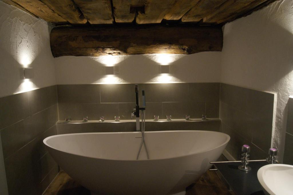a bath tub in a bathroom with lights on the wall at Charming 3½ room cottage in Valposchiavo in Poschiavo