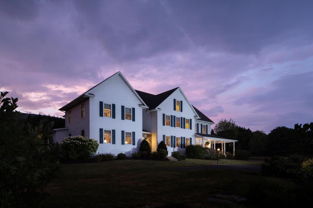 una casa blanca con las luces encendidas al atardecer en Apple Pony Inn en Boalsburg