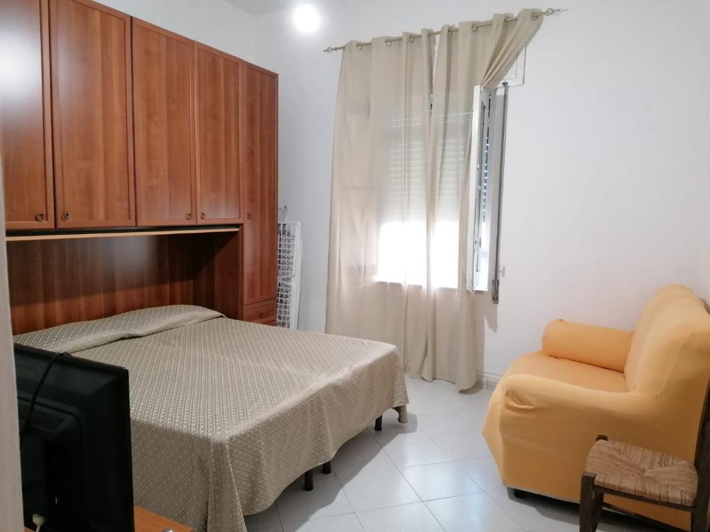 ein Schlafzimmer mit einem Bett, einem Stuhl und einem TV in der Unterkunft Appartamento Bent el Rhia in Pantelleria