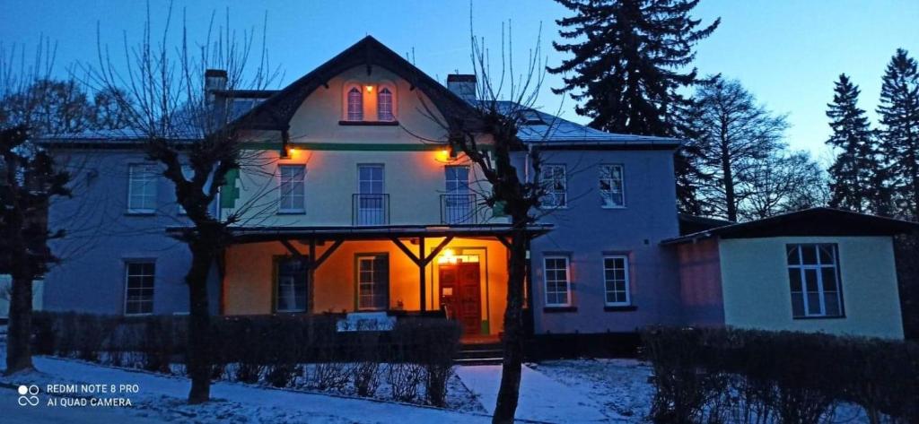 ein Haus mit eingeschaltetem Licht im Schnee in der Unterkunft Willa Dunajec in Kudowa-Zdrój