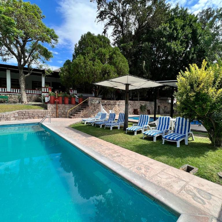 a swimming pool with lounge chairs and an umbrella at Lourdes Hotel Campestre in Tierranueva
