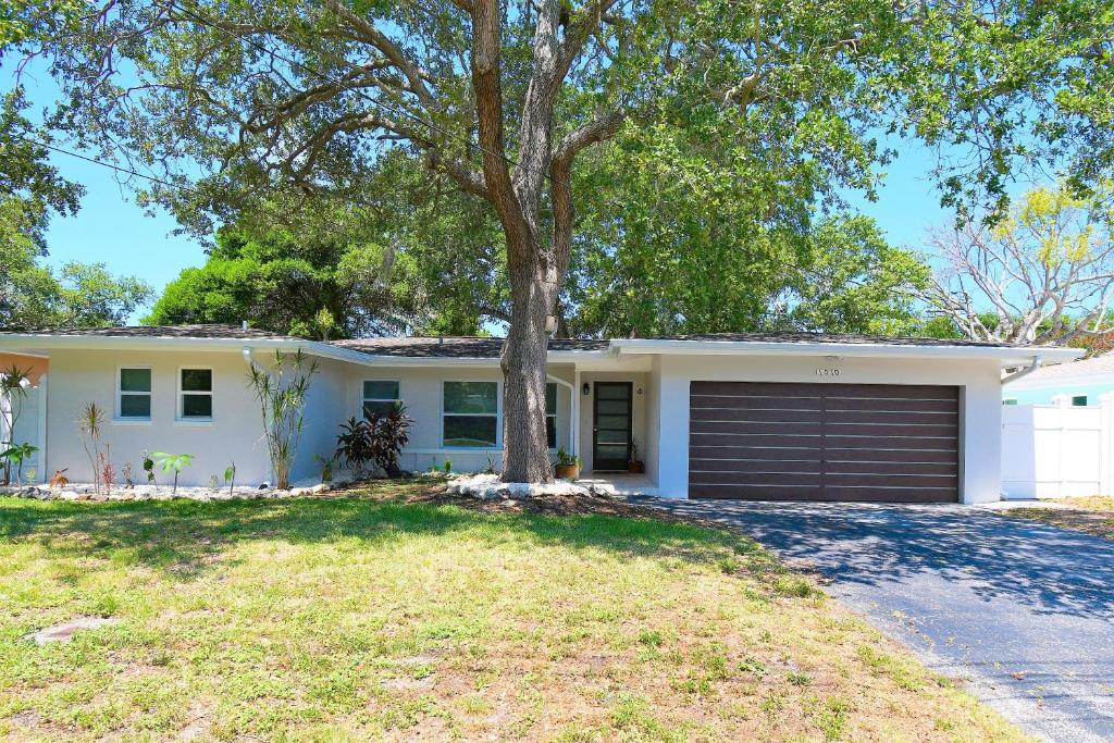 a house with a tree and a garage at CasaBreeze Cozy Creek House/IRB&Clearwater Beach! in Largo