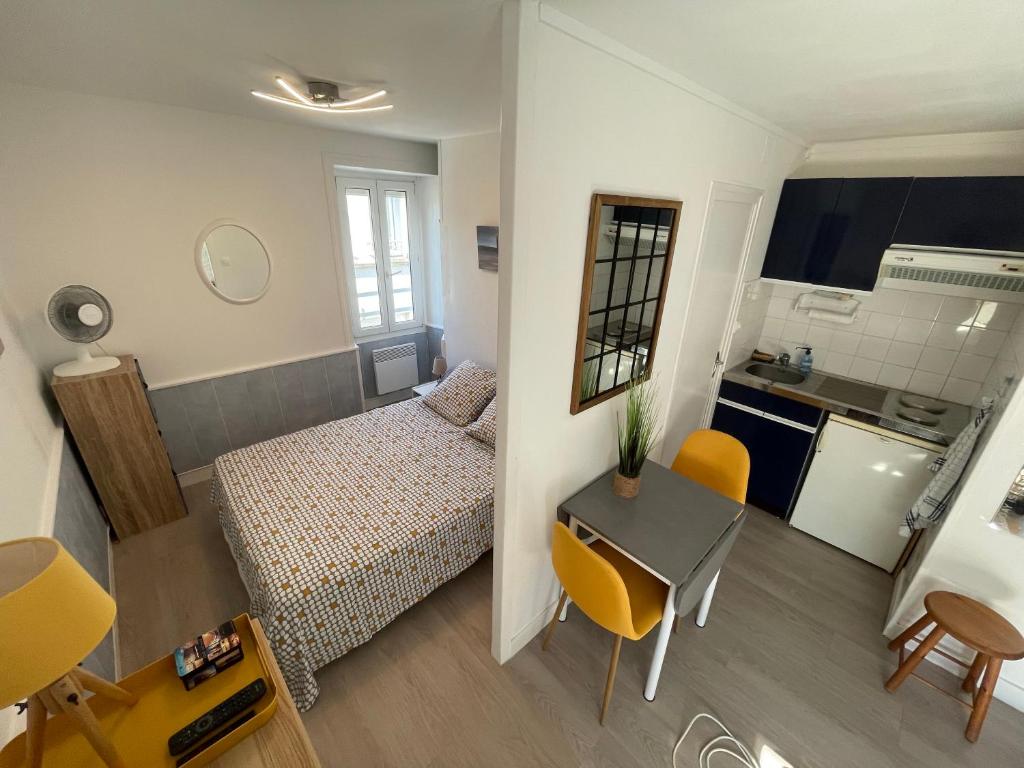 een klein appartement met een bed en een tafel en stoelen bij Appt FOURAS Centre Ville 50m de la Mer in Fouras