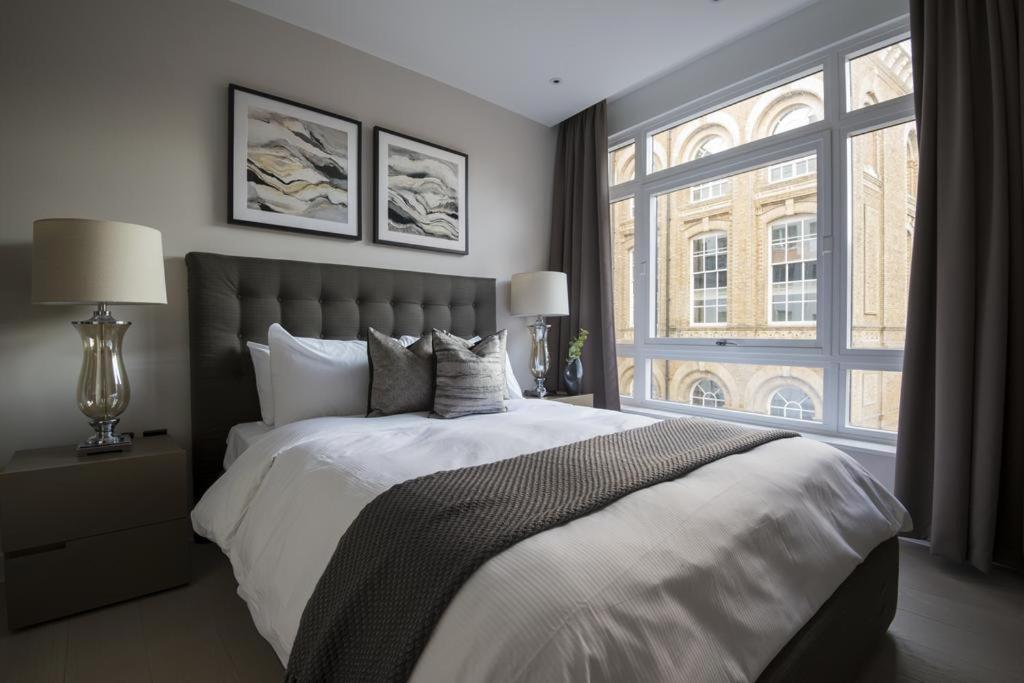Buckingham Palace Residences by Q Apartments في لندن: غرفة نوم بسرير كبير ونافذة كبيرة