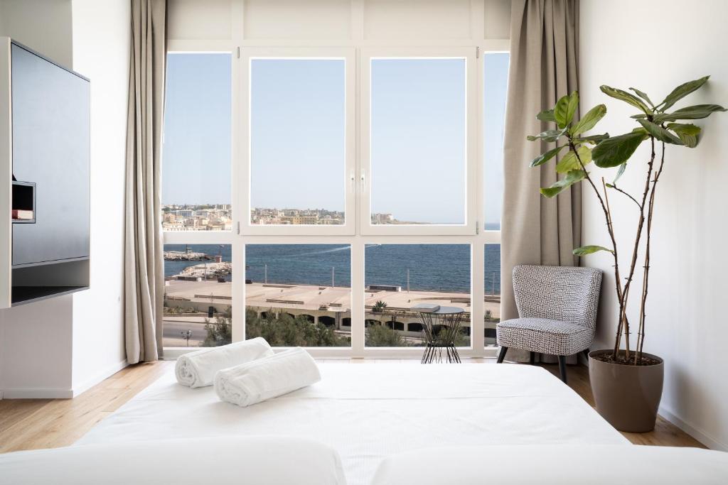 a bedroom with a white bed and a large window at La Vacanza Ortigia in Siracusa