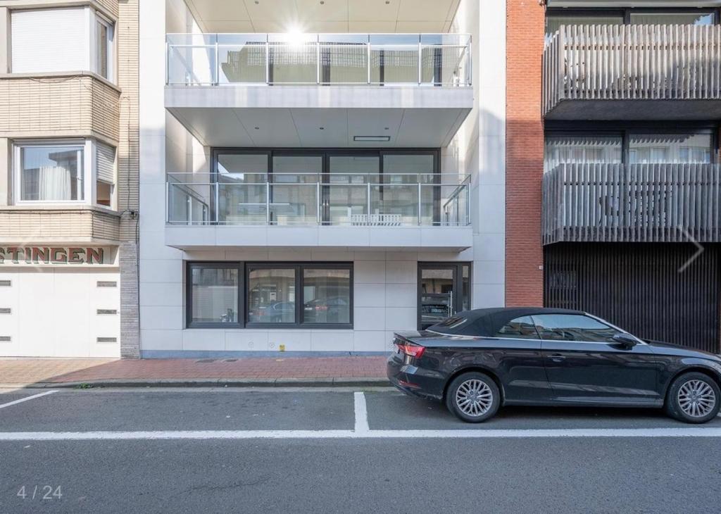 a black car parked in a parking lot in front of a building at Beautiful 3 bedroom garden-appartment near Knokke-Strand Beach Bar in Knokke-Heist