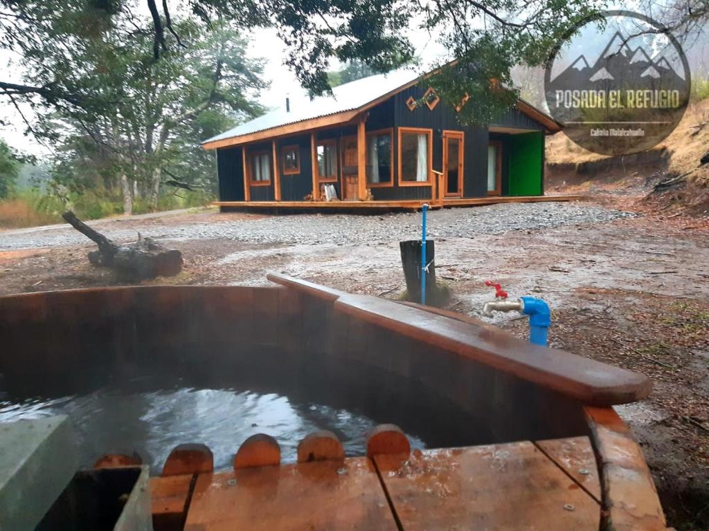 una casa con una piscina de agua frente a ella en Cabaña Posada El Refugio, en Malalcahuello