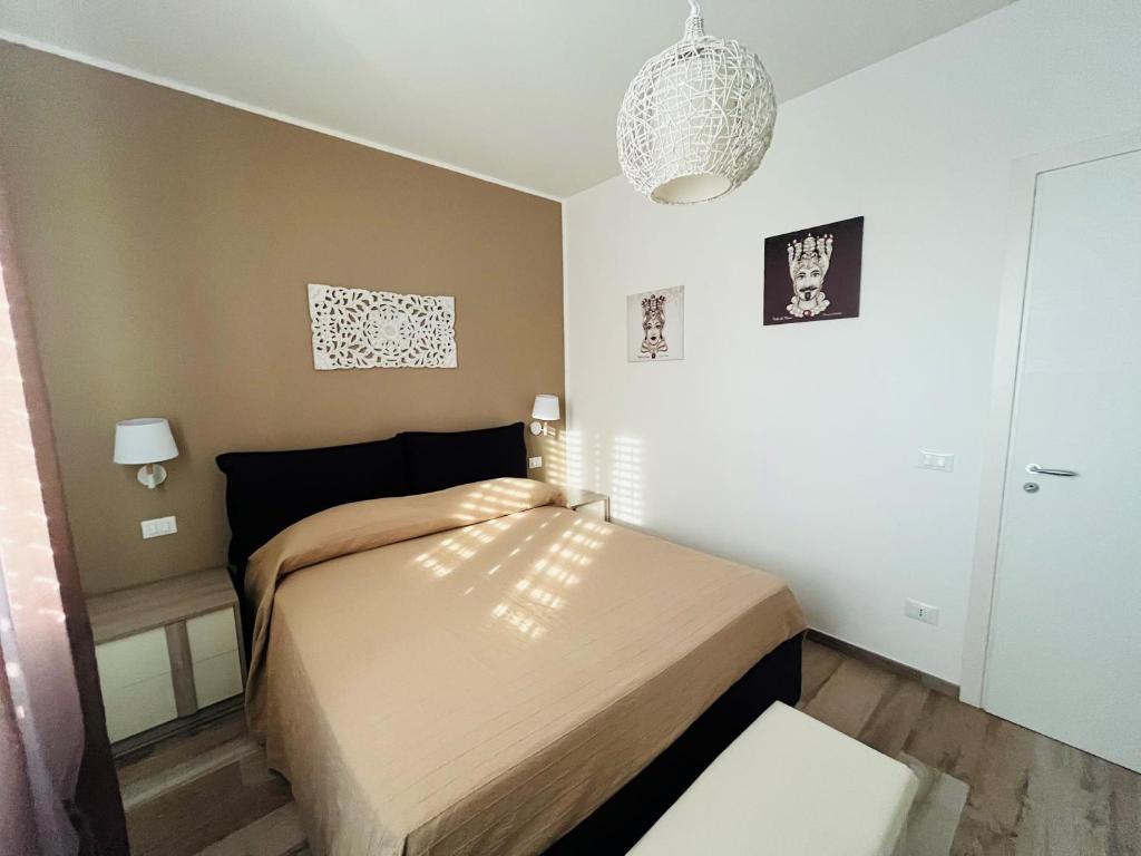 サン・ヴィート・ロ・カーポにあるCasa Corallo San Vitoのベッドとシャンデリア付きの小さなベッドルーム1室