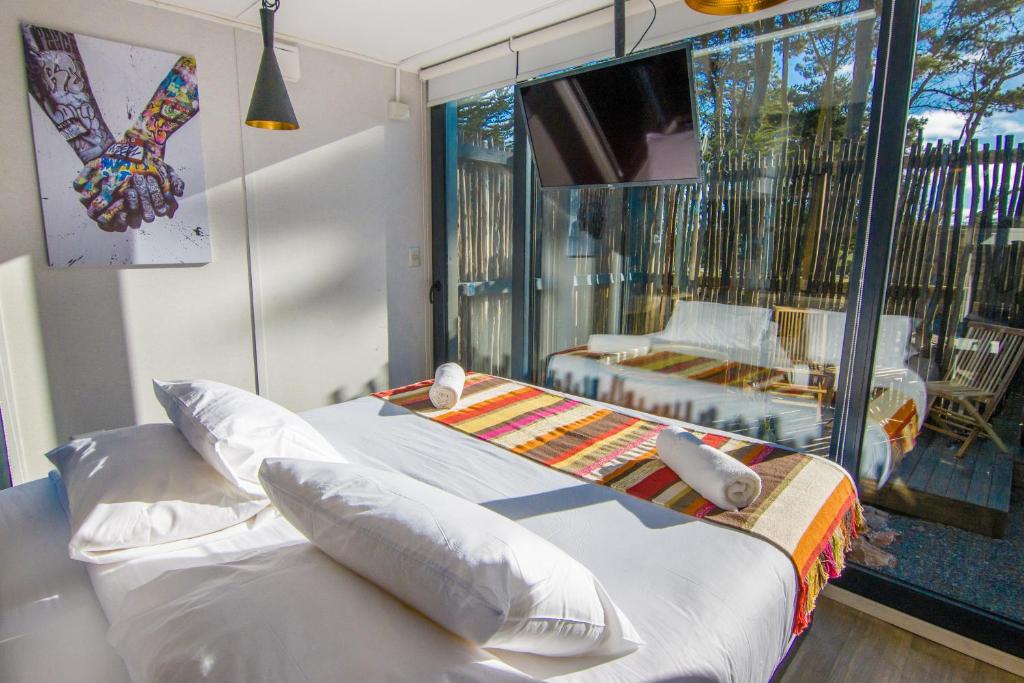 1 dormitorio con cama y vistas a un balcón en Quisquito Lodge & Spa - Punta de Lobos - Tina 24 Hrs en Pichilemu
