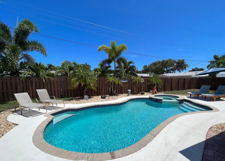 uma piscina num quintal com cadeiras e uma cerca em Paradise 4 min to the Beach with Private Heated Pool em Deerfield Beach