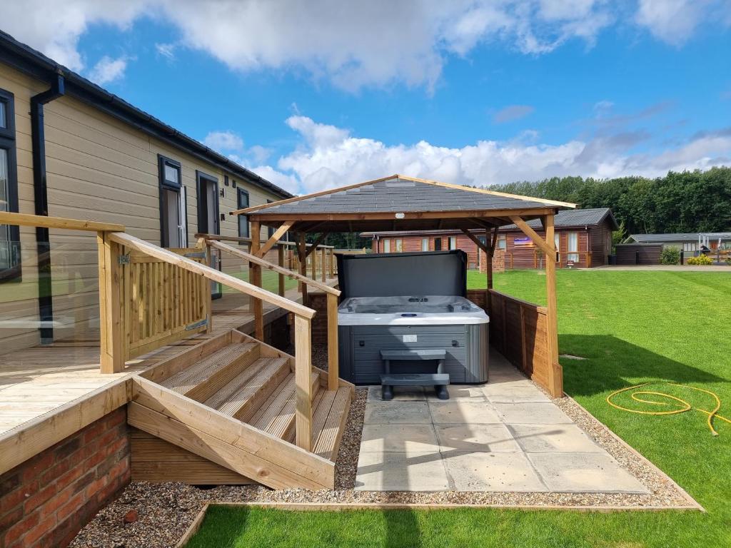 a deck with a wooden gazebo and a grill at Remarkable 2-Bed Luxury Lodge in Routh with hottub in Routh