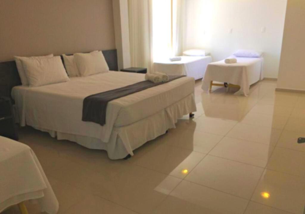 Un dormitorio con una gran cama blanca y una mesa en Scenarium Hotel en Recife