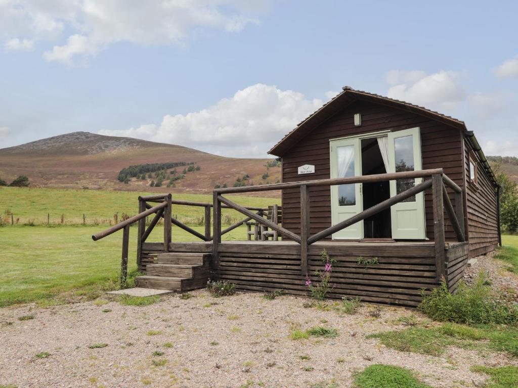 a small cabin in a field with mountains in the background at Ben View in Keith