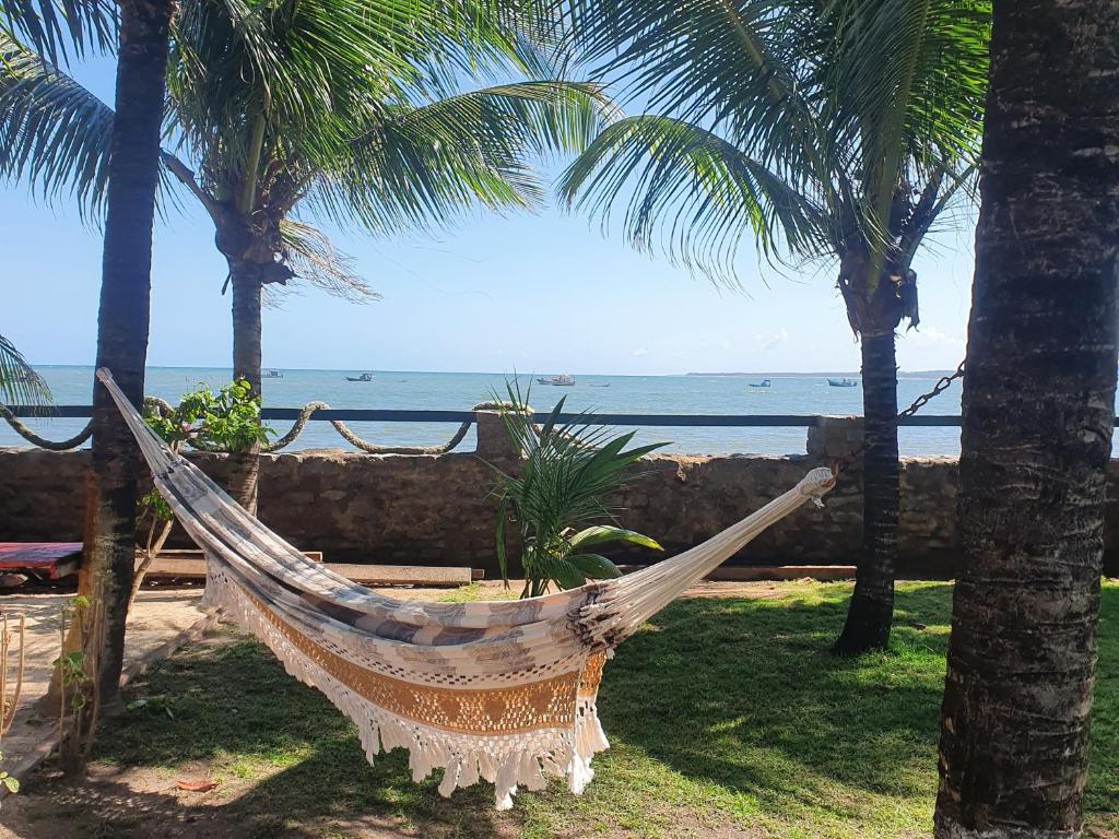 een hangmat hangend aan twee palmbomen bij de oceaan bij Casarão do Pontal in Coruripe