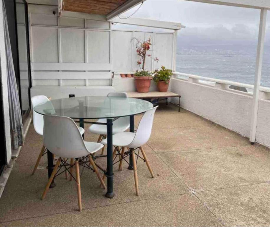 una mesa de cristal y sillas en un balcón con vistas al océano en Departamento Reñaca, Sector 5, en Viña del Mar