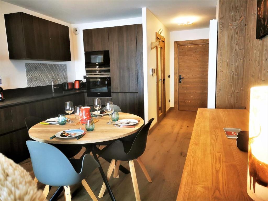 une cuisine et une salle à manger avec une table et des chaises en bois dans l'établissement Beau T2 classé 3*, centre Les Gets, terrasse, parking, locaux à skis et vélos - FR-1-598-88, aux Gets