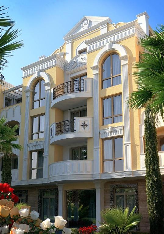 a large yellow building with windows and palm trees at FLORENCE SUITES APART HOTEL in Sveti Vlas