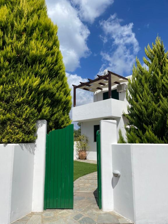 uma cerca branca com uma porta verde em frente a uma casa em Sunny Villa em Kissamos