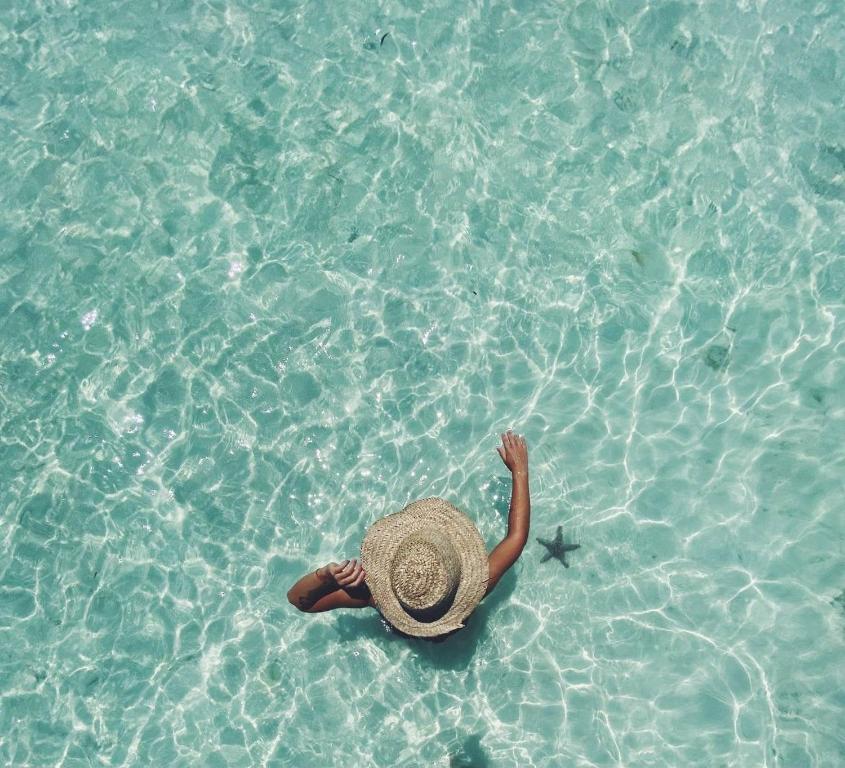 a person with a hat laying in the water at Lighthouse Guesthouse in Nungwi