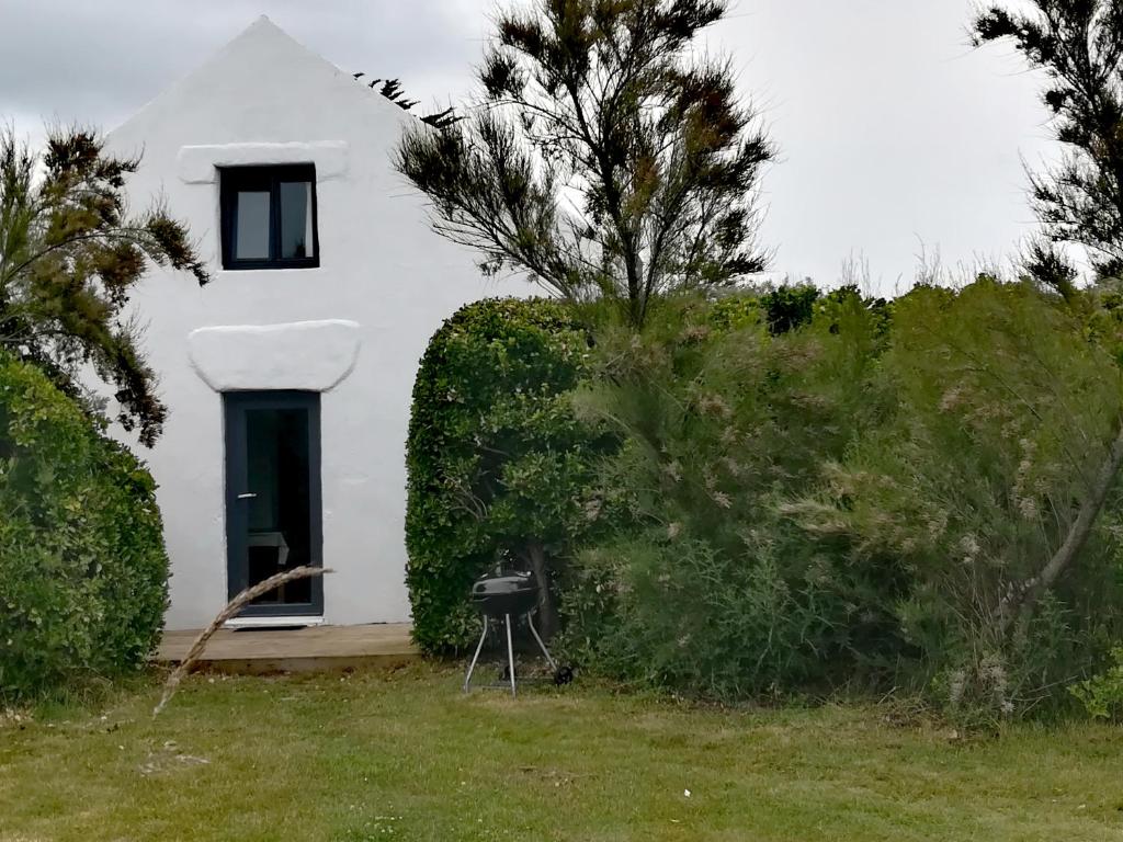 a white house with a door and some bushes at TY MERVENT, l'océan à 500 m in Saint-Jean-Trolimon