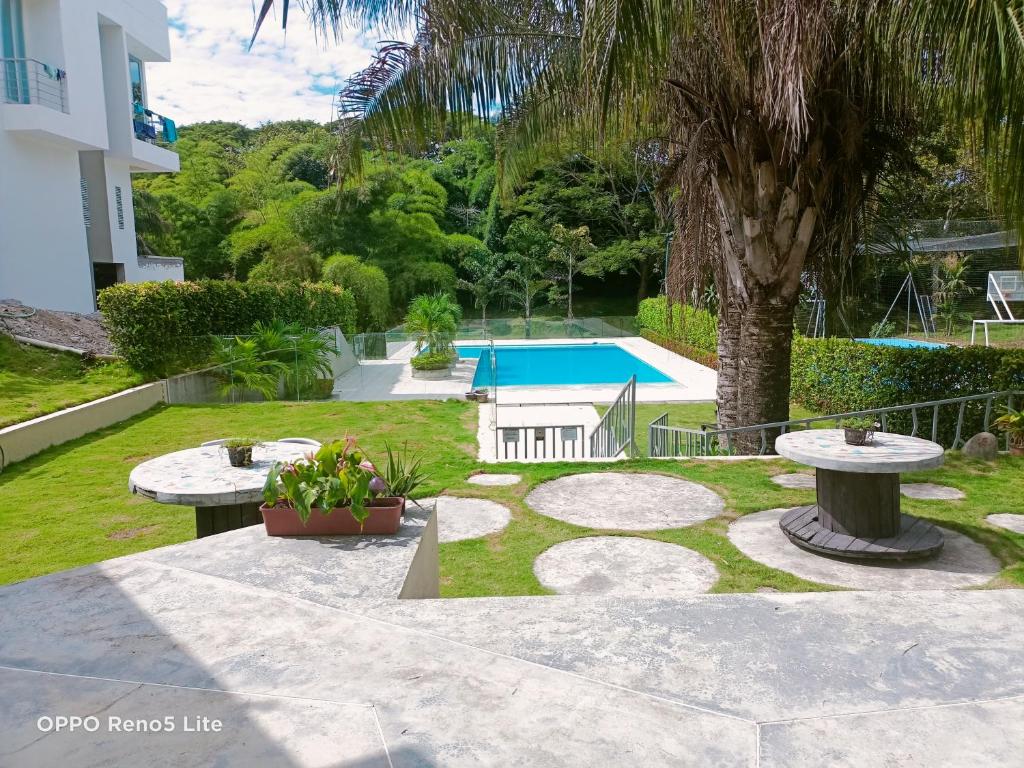 un jardín con 2 mesas y una piscina en Casa vacacional condominio bambú, en Carmen de Apicalá