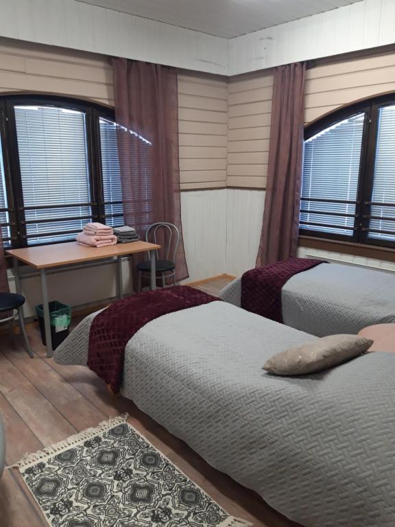 a bedroom with two beds and a table and windows at Jaalan Tienristi in Kouvola