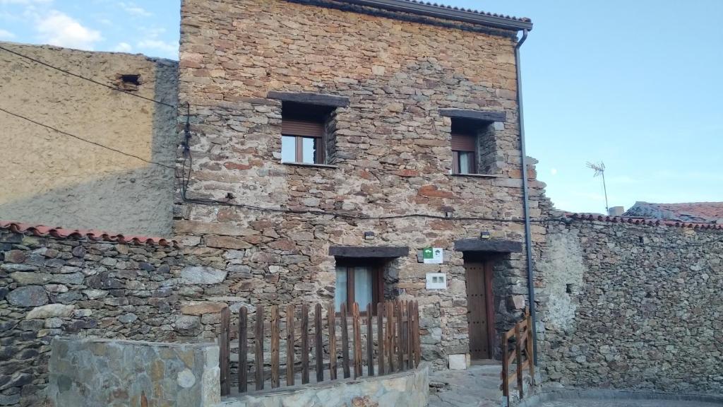 um antigo edifício de pedra com um portão de madeira em La Casa Rural de Alicia em Bustares