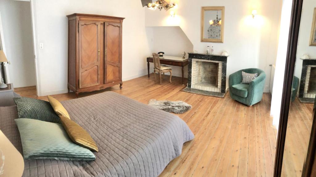 ein Schlafzimmer mit einem Bett, einem Kamin und einem Stuhl in der Unterkunft Ty Sarah Lomener in Lomener