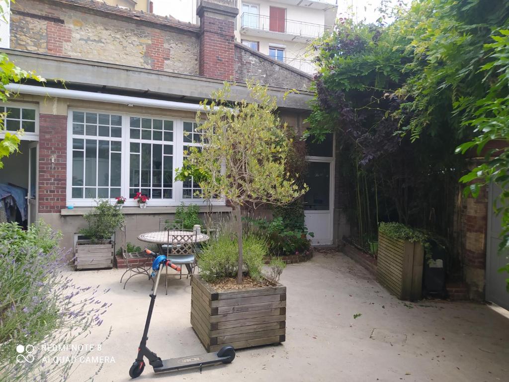 a garden with a scooter in front of a house at Maison de maître, un coin de verdure en hyper centre in Lisieux