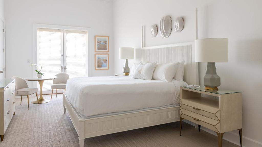 a white bedroom with a white bed and a table at Oyster Bay Boutique Hotel in Pensacola