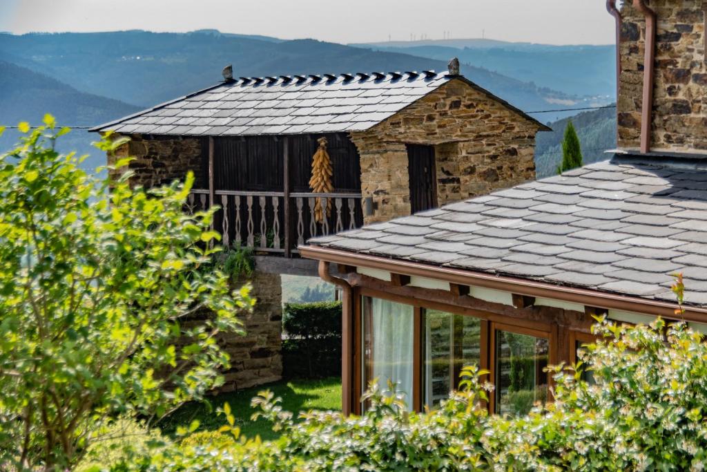 a stone house with a balcony and mountains in the background at Complejo Rural Lar de Vies in A Pontenova