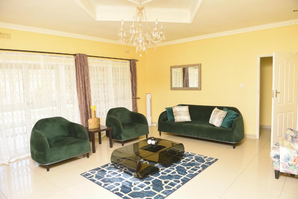 una sala de estar con muebles verdes y una lámpara de araña. en AZB Cozy Homes. Elegant 4 bedroom home in Area 49, Lilongwe en Lilongüe