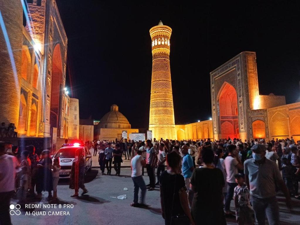 a crowd of people standing in front of a mosque at night at Suleyman hotel in Bukhara