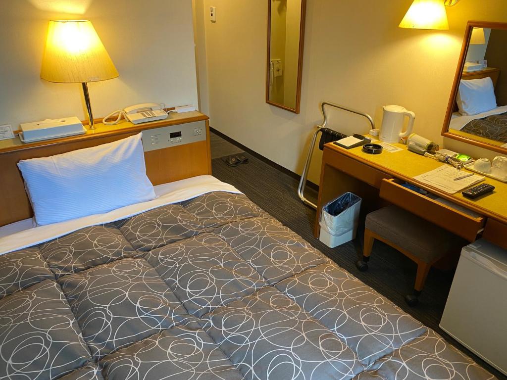 福井市にあるアズイン福井(エースイン福井)のベッド、デスク、コンピュータが備わるホテルルームです。